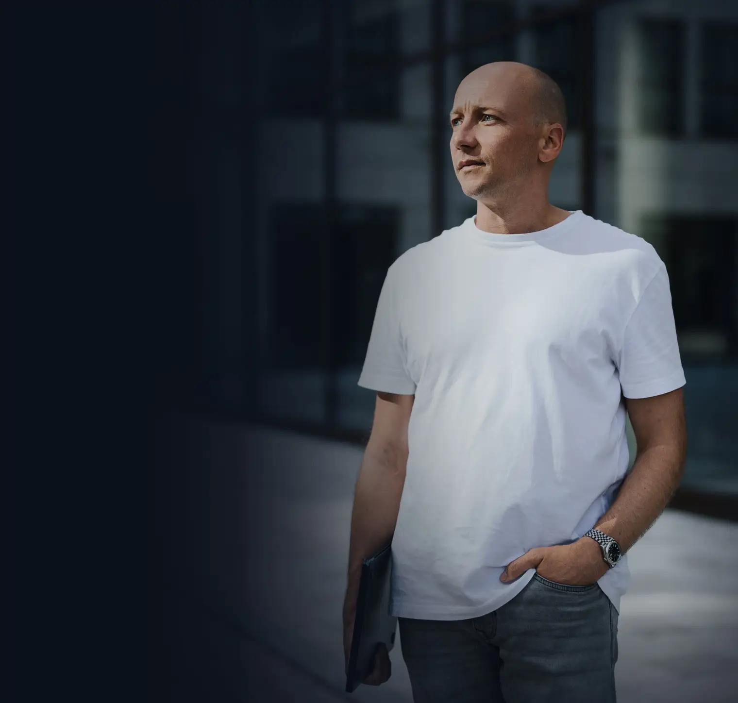 Fabian Ullmann vor einer Glasfassade, Laptop unter dem Arm